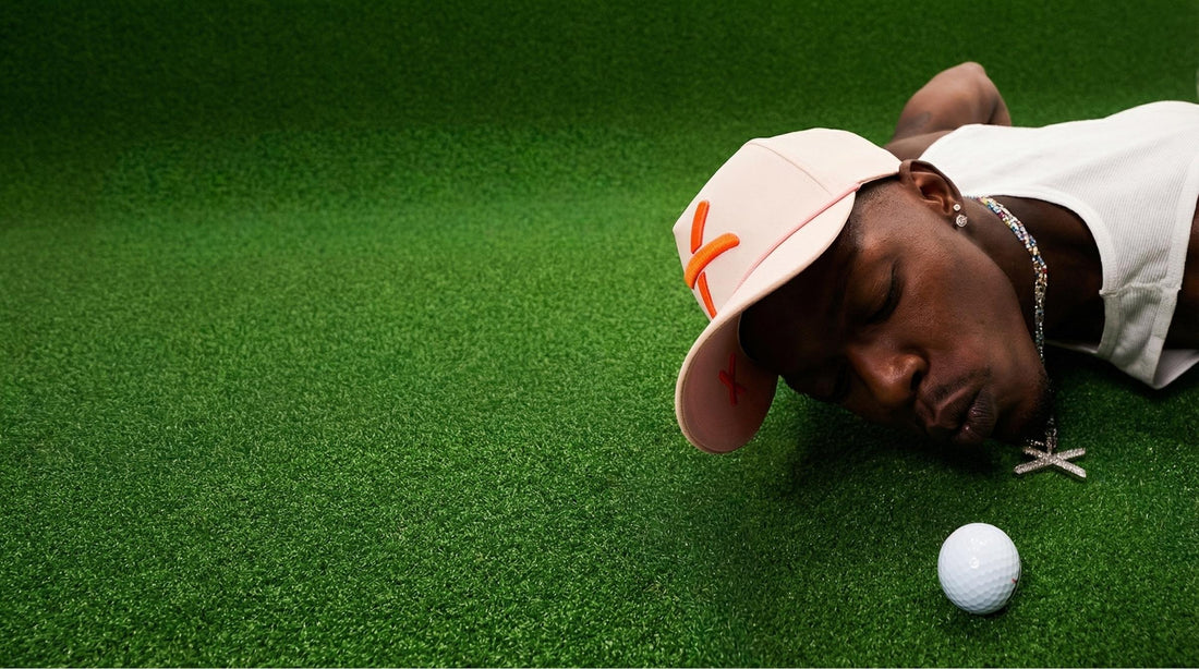 Jazz Chisholm Jr lying on a green surface with a golf ball 