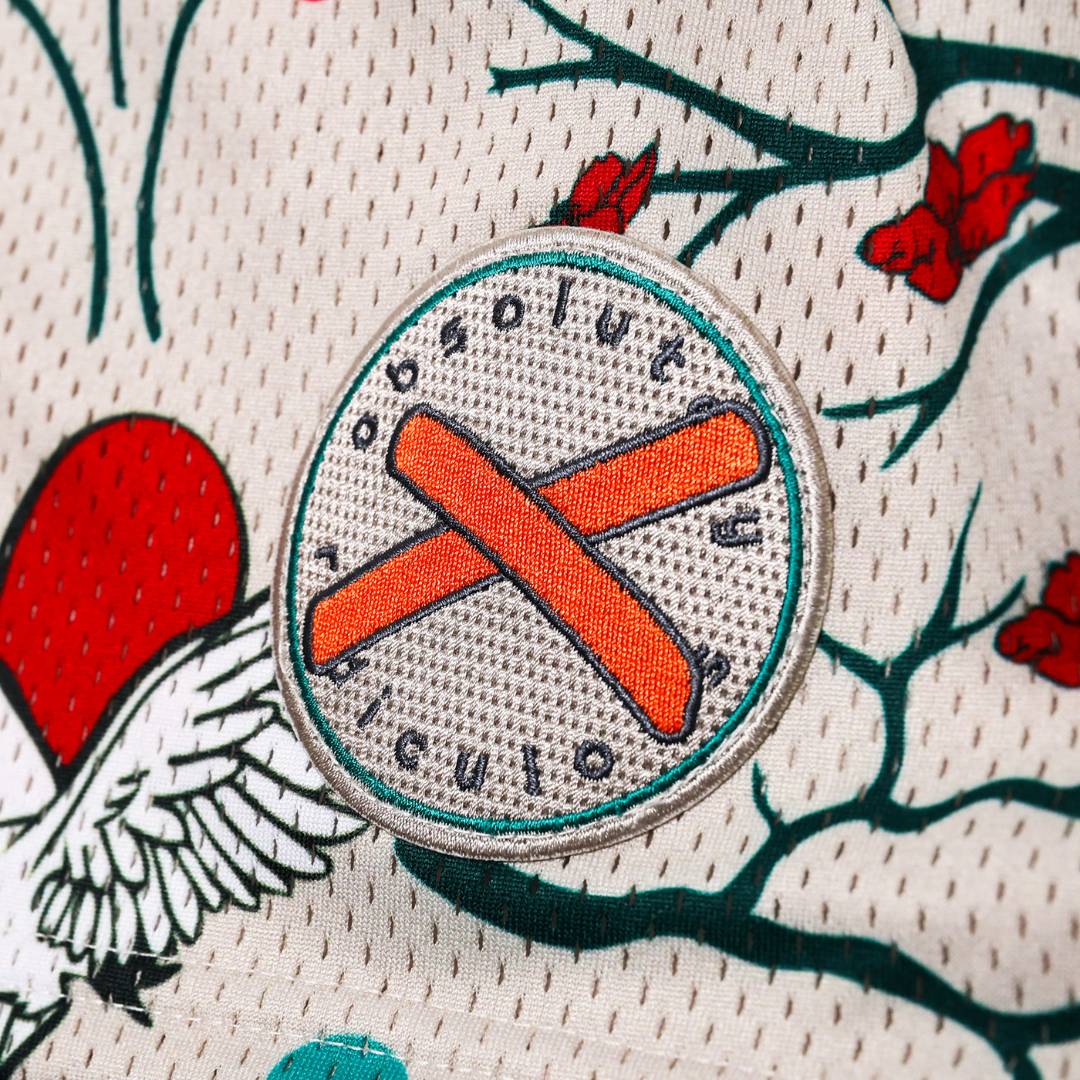 Circular patch with 'absolutely ridculous' branding on the background of the grandma's wallpaper shorts with red and green elements.