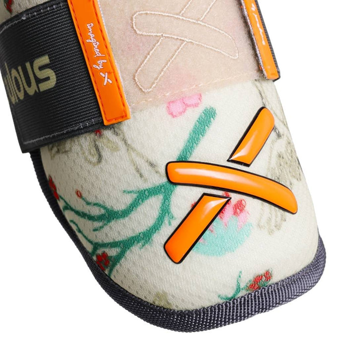 Translation missing: ja.“Angled close-up of the elbow guard showing floral pattern, strap details, and orange X accent.”